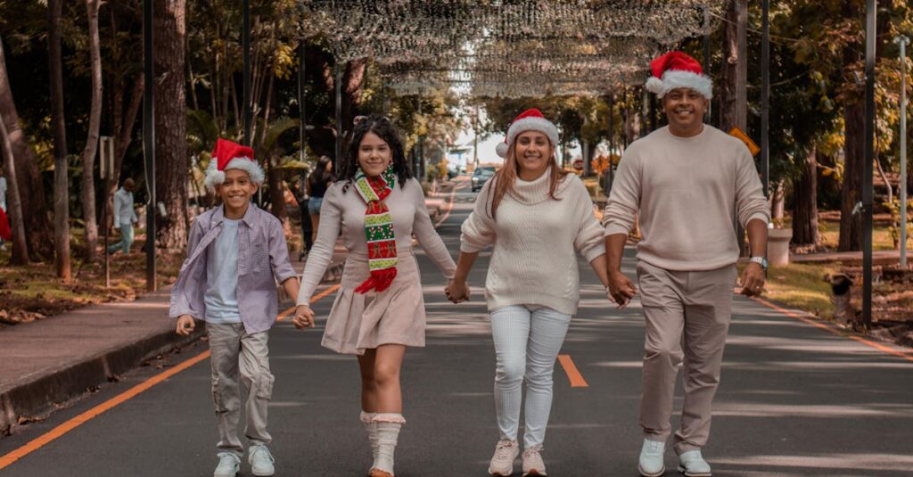 A joyful family walks down a decorated street wearing Christmas hats, symbolizing holiday spirit.