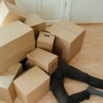 A person overwhelmed by cardboard boxes during a home move, symbolizing stress and relocation.